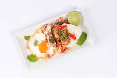 Pirinç beyaz arka plan üzerinde karıştırılır kıyılmış domuz eti, kalamar, fesleğen ve kızarmış yumurta (güneşli yukarı) ile tepesinde.