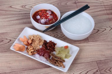 Pirinç gruel ve ahşap garnitür. (Kurutulmuş rendelenmiş domuz eti, Çin sosis, gevrek balık, sosis, kızarmış bebek istiridye, dilimlenmiş kırmızı soğan, turşu Çin lahanası, Baharatlı sardalya salatası ve arpacık )