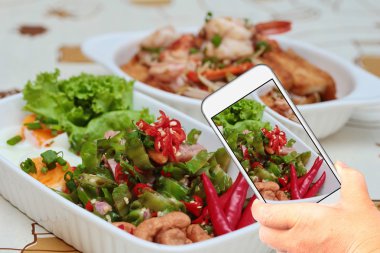 Arkadaş sosyal ağ paylaşmak için fotoğraf baharatlı ekşi sosis salatası çekmek için akıllı telefon kullanarak.