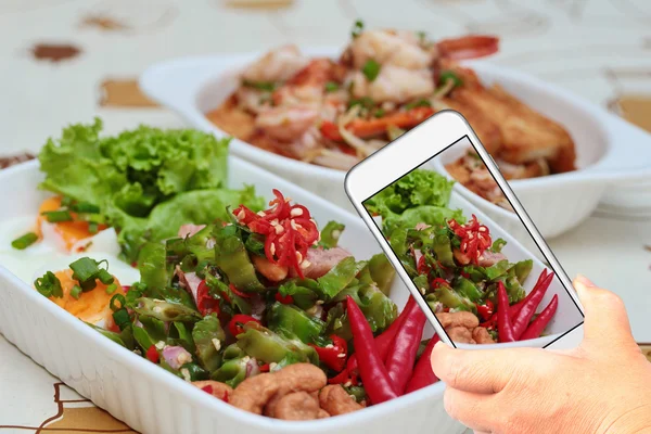 Amigo usando el teléfono inteligente para tomar foto picante ensalada de salchichas agria para compartir la red social . — Foto de Stock