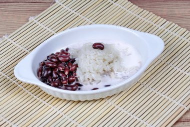 Black bean and sticky rice in sweet coconut cream topped coconut milk on bamboo. Side view. clipart