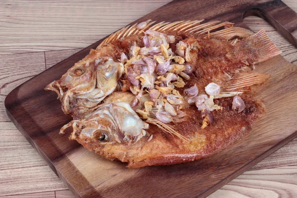 Deep fried fish ,Nile tiapia, with crispy garlic on butcher served. Side view. — Stock Photo, Image