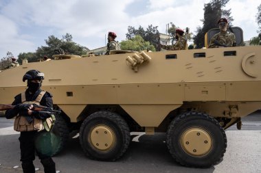 Şam, Suriye. 8 Aralık 2025. Askeri üniformalı askerler ve miğferler şehrin caddesinde büyük bir zırhlı aracın üzerinde ve yanında dururlar..