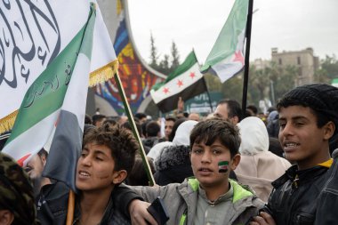 Şam, Suriye. 8 Aralık 2025. Genç çocuklar, ellerinde birkaç Suriye bayraklarıyla halka açık bir toplantıya katılıyorlar..