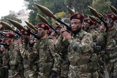 Şam, Suriye. 8 Aralık 2025. Askeri kamuflaj üniforması ve kestane rengi bereliler roket güdümlü bomba fırlatıcıları taşırken bir arada yürürler..