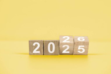 Wooden blocks arranged to show the year 2025, symbolizing the upcoming year and new beginnings, set against a vibrant yellow backdrop.