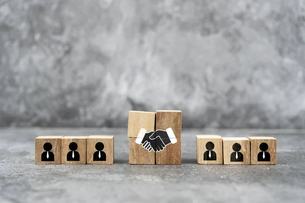 Ahşap bloklar bir iş anlaşması ve takım çalışmasını tasvir etmek için düzenlenmiştir. Gri arkaplana karşı bir şirket ortamında işbirliği ve ortaklığı sembolize eder..