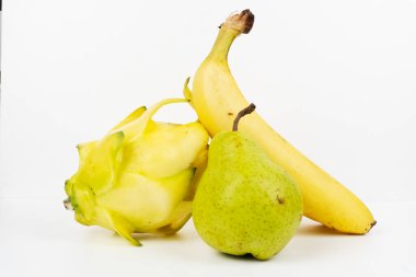 Üç farklı meyve bir muz, armut ve sarı ejderha meyvesini bir arada gösteriyor..