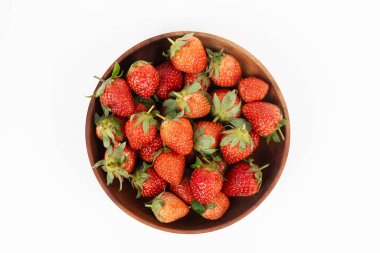 Taze kırmızı çilekler koyu bir ahşap kaseyi doldurur. Sağlıklı yaz meyvelerinin manzarasını gösterir..