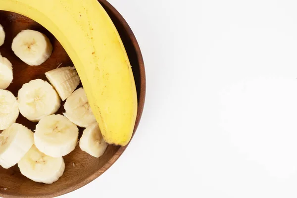 Tam muz ve dilimler tahta bir kasenin sağ tarafını dolduruyor. Beyaz arka planda kopya alanı var..