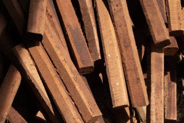 Yığılmış kereste parçaları, yakın plan desenli arka plan, sıcak güneş ışığı.