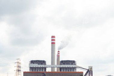 Yeşil alanlar ve kırsal manzaranın ortasındaki elektrik santrali ve bacalarla sanayi bölgesi