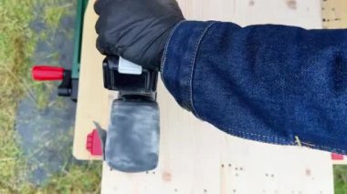 Profesyonel marangoz arka bahçedeki kaba tezgahta odun cilalamak için elektrikli zımpara makinesi kullanıyor. Tasarım, marangozluk, işçilik ve el işi konsepti. Yüksek kalite 4k görüntü