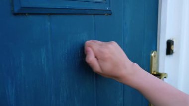 Evin önünden bir genç kapıyı çalıyor, yakın plan..