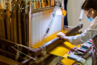 A female worker working on a Chinese Ancient weaving machine in the museum of jiangning weaving bureau, in Nanjing, China.
