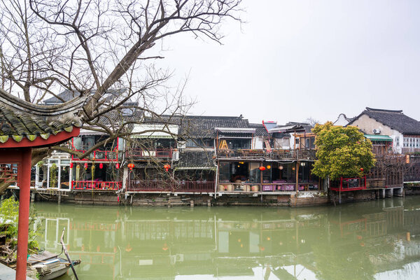 Wooden historic buildings at the bank of canal river in Zhujiajiao in a rainy day, an ancient water town in Shanghai, built during Ming and Qing Dynasties of China