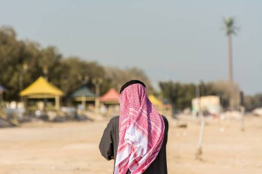  Suudi Arabistan Krallığı Dammam 'daki korniş parkın arka planına sahip geleneksel Arap kıyafetleri giyen bir Suudi Arabistan' lı.