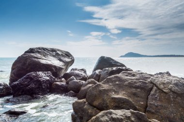 Dalgalar denizi Yangxi, Çin Yangjiang 'ın kayalık kıyılarına taşları serpiyor.