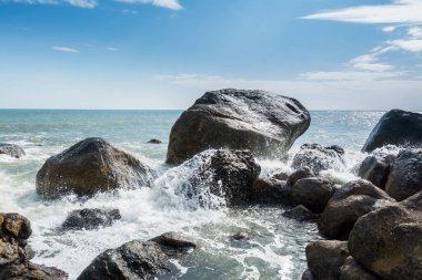 Dalgalar denizi Yangxi, Çin Yangjiang 'ın kayalık kıyılarına taşları serpiyor.