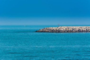 Abu Dabi, Birleşik Arap Emirlikleri 'ndeki Corniche parkındaki Basra Körfezi' ndeki mavi deniz ve taş baraj..