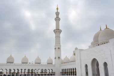Beyaz bulutlu gökyüzüne karşı Beyaz Cami 'nin minare ve kubbeleri aynı zamanda Şeyh Zayed Büyük Camii olarak da adlandırılır, Pers, Babür ve Fas camii mimarisinden esinlenilmiştir.