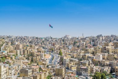 Amman şehrinin çok sayıda binası ve Ürdün ulusal bayrağı, Ürdün 'ün başkenti ve en kalabalık şehri, Arapça' da Jabal el-Qal 'a olarak bilinen Amman Kalesi' nin görüşü.