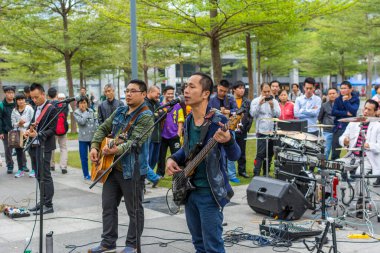 Shenzhen yerel sokak grubunun iki adamı Shenhzhen Central Park 'ında gitar çalıp şarkı söylüyorlar..