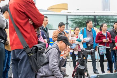 Çinli bir adam kamerasını izliyor ve Çin geleneksel müzik enstrümanı Erhu 'yu Çin' in Shenzhen şehrinde çalan bir adamı kaydediyor.