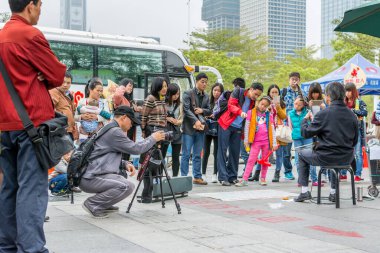 Çinli bir adam kamerasını izliyor ve Çin geleneksel müzik enstrümanı Erhu 'yu Çin' in Shenzhen şehrinde çalan bir adamı kaydediyor.
