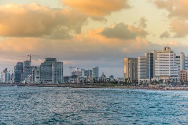 Tel Aviv 'deki eski şehir Jaffa' sı yakınlarında alacakaranlık altında modern gökyüzü çizgileri ve lüks oteller ve körfezde birçok turist ve yerli yüzüyor..