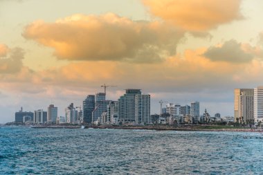 Tel Aviv 'deki eski şehir Jaffa' sı yakınlarında alacakaranlık altında modern gökyüzü çizgileri ve lüks oteller ve körfezde birçok turist ve yerli yüzüyor..