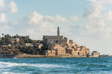 Eski Jaffa şehri, Tel Aviv 'in eski liman ve kıyı şeridi günbatımının altında ve birçok turist Akdeniz' de yüzüyor ve sörf yapıyor..