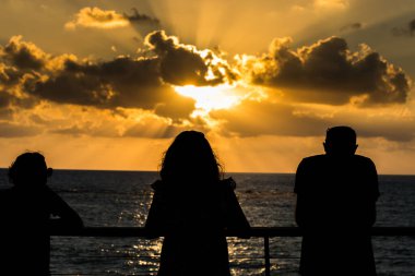 Güzel gün batımı ve altın alacakaranlık, ve bulutlar, İsrail 'de Akdeniz kıyısında duran ve Tel Aviv, İsrail' de gün batımını izleyen insan siluetleri..