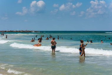 Birçok turist ve yerel halk güneşli bir günde güneşlenmeyi, yüzmeyi ve sporu ve İsrail 'in Tel Aviv kentindeki Akdeniz kıyısının kumlu sahillerini seviyor.