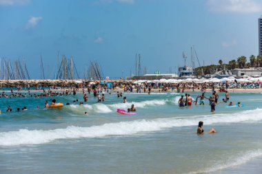 Birçok turist ve yerel halk güneşli bir günde güneşlenmeyi, yüzmeyi ve sporu ve İsrail 'in Tel Aviv kentindeki Akdeniz kıyısının kumlu sahillerini seviyor.
