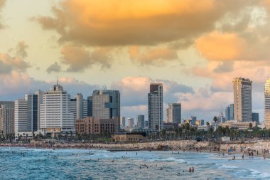Tel Aviv 'deki eski şehir Jaffa' sı yakınlarında alacakaranlık altında modern gökyüzü çizgileri ve lüks oteller ve körfezde birçok turist ve yerli yüzüyor..