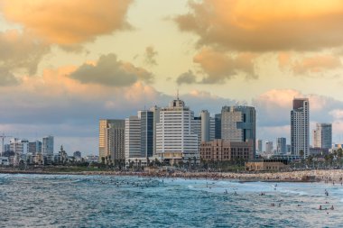 Tel Aviv 'deki eski şehir Jaffa' sı yakınlarında alacakaranlık altında modern gökyüzü çizgileri ve lüks oteller ve körfezde birçok turist ve yerli yüzüyor..