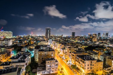 İsrail 'in Tel Aviv limanı yakınlarındaki kumsalda modern gökdelenler ve lüks otellerle Tel Aviv şehrinin gece hava manzarası.