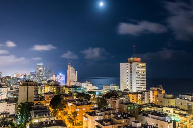İsrail 'in Tel Aviv limanı yakınlarındaki kumsalda modern gökdelenler ve lüks otellerle Tel Aviv şehrinin gece hava manzarası.
