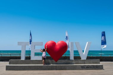 İsrail 'deki Tel Aviv limanındaki I Love Tel Aviv heykeline tırmanan küçük bir kız.. 