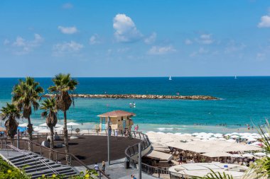Birçok turist tatillerini İsrail 'in Tel Aviv plajında, şemsiyelerin altında geçirirler..