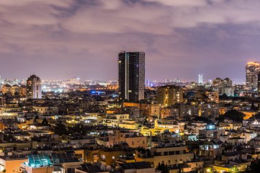 İsrail 'in Tel Aviv limanı yakınlarındaki kumsalda modern gökdelenler ve lüks otellerle Tel Aviv şehrinin gece hava manzarası.