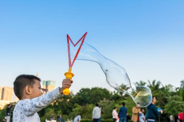 Longtan Park, Shenzhen, Çin 'de sabun köpüğü yapan Çinli bir çocuk.