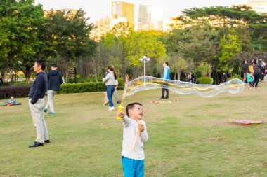 Longtan Park, Shenzhen, Çin 'de sabun köpüğü yapan Çinli bir çocuk.