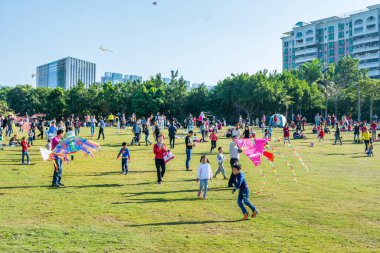 Longgang, Shenzhen 'deki çayırda güneşli bir haftasonunda insanlar uçurtma uçuruyor.