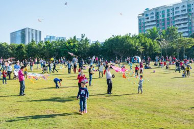 Longgang, Shenzhen 'deki çayırda güneşli bir haftasonunda insanlar uçurtma uçuruyor.