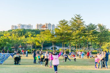 Longgang, Shenzhen 'deki çayırda güneşli bir haftasonunda insanlar uçurtma uçuruyor.