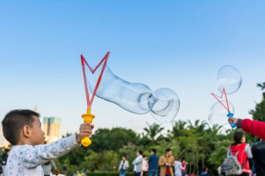 Longtan Park, Shenzhen, Çin 'de sabun köpüğü yapan Çinli bir çocuk.