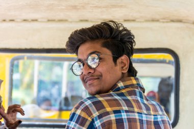 Hindistan Haydarabad 'daki Nehru Zooloji Parkı mini treninde güneş gözlüğü takan Hintli genç adam portresi