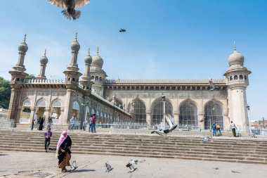 Müslüman hacılar Mekke Mescidi 'ne mavi gökyüzüne ve Hyderabad' daki ünlü bir anıt olan gökyüzünde uçan güvercinlere karşı yürüyorlar. 
